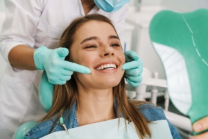 une jeune fille qui sourit. son chirurgien dentiste lui explique les soins dentaires a réaliser
