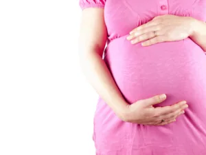 Femme enceinte en robe rose tenant son ventre