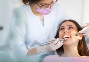 Dentiste au masque rose soignant une patiente souriante