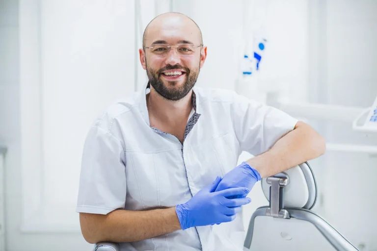 Chirurgien-dentiste souriant avec des gants bleus dans son cabinet