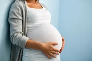 Femme enceinte en t-shirt blanc tenant son ventre