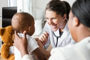 Pédiatre souriante examinant un bébé tenu par sa mère