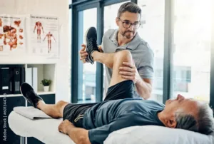 Kinésithérapeute étirant la jambe d’un patient allongé sur une table