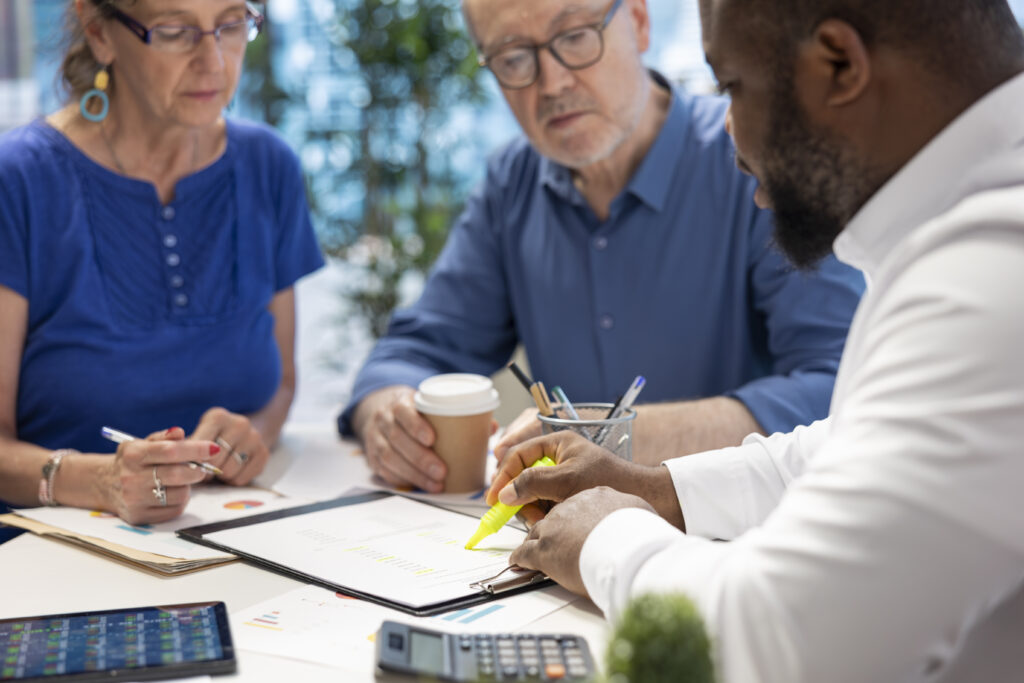 Courtier en assurances expliquant les clauses d’un contrat à un couple de clients