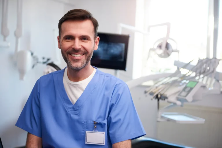 Chirurgien-dentiste souriant en tenue bleue dans son cabinet