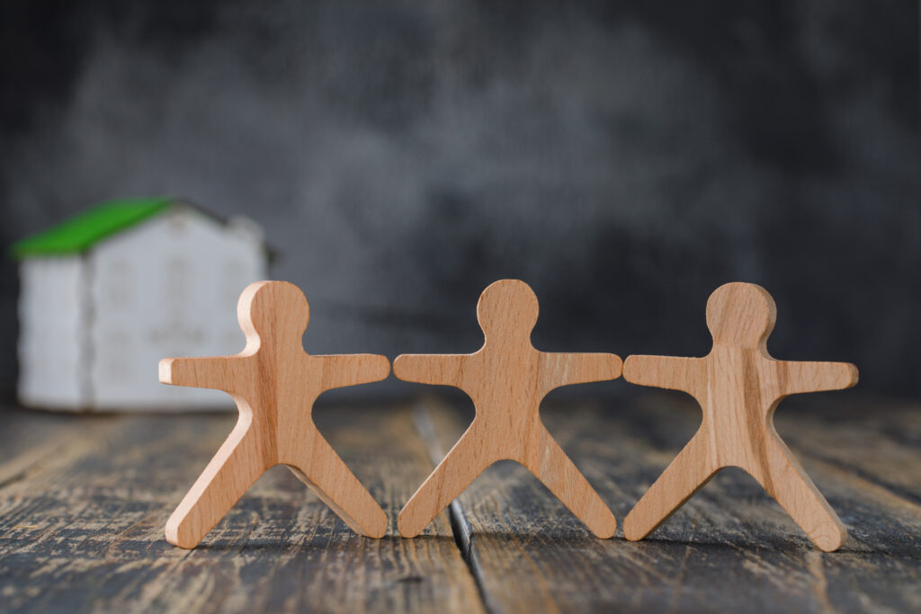 Figurines en bois d’une famille et maquette de maison, symbole de protection familiale