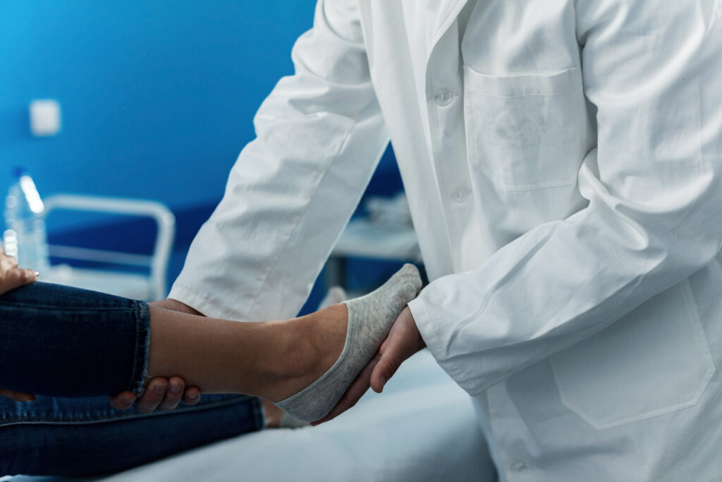 Médecin en blouse blanche examinant le pied d’un patient
