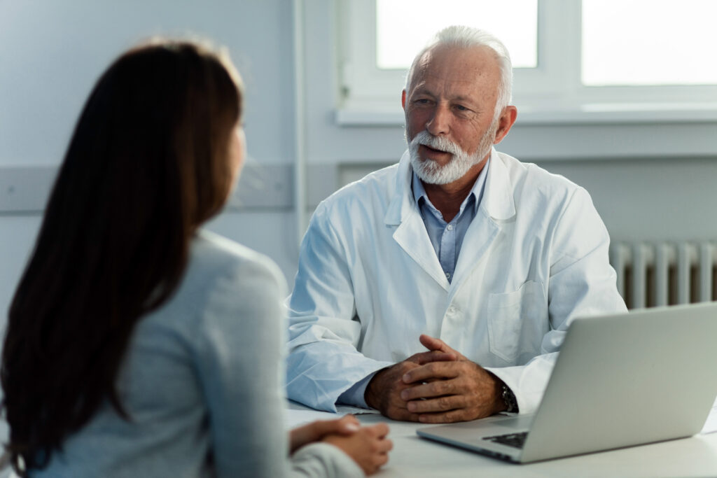 Médecin senior en consultation avec une patiente devant son ordinateur
