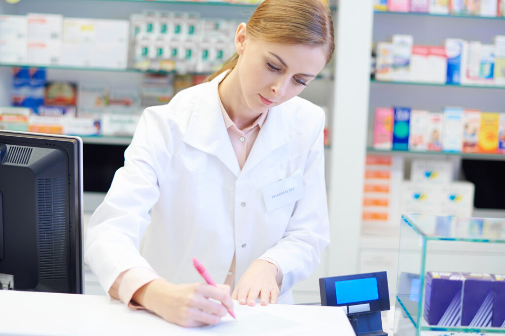 Pharmacienne remplissant un document au comptoir de sa pharmacie