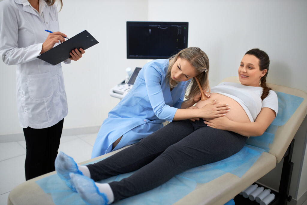 Sage-femme examinant le ventre d’une femme enceinte allongée