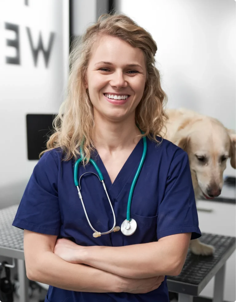 Vétérinaire souriante, bras croisés, avec un chien à ses côtés