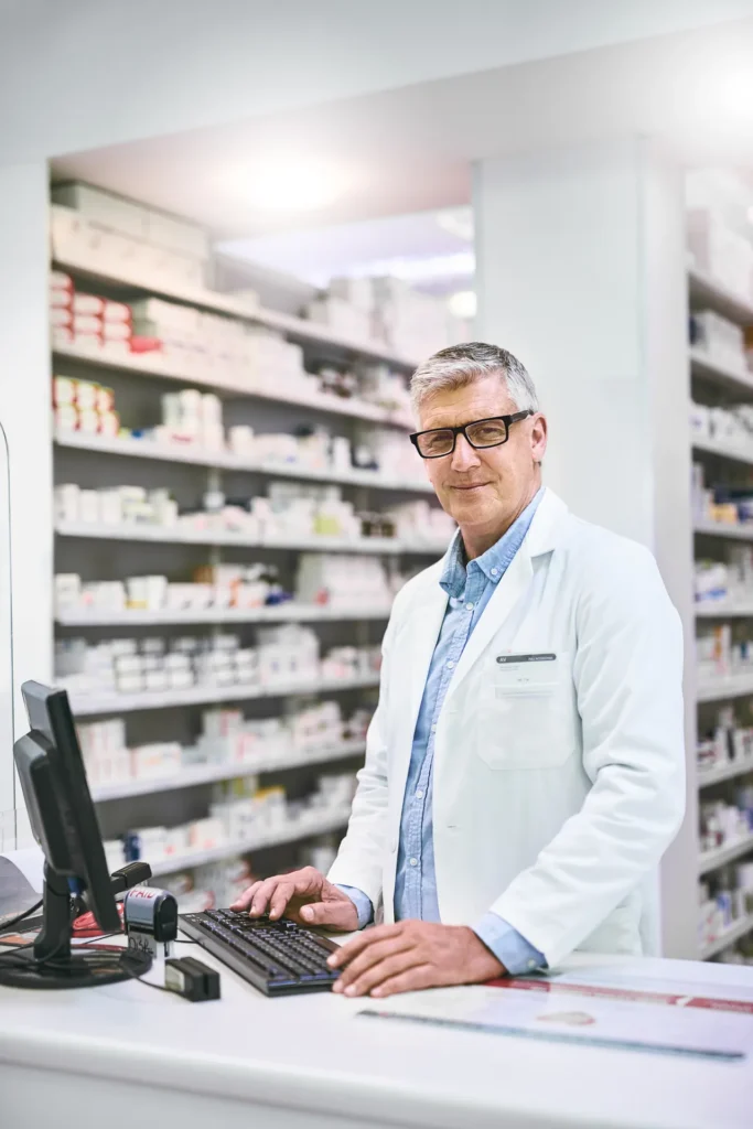 Pharmacien à son ordinateur dans son officine – assurance de prêt pour pharmaciens