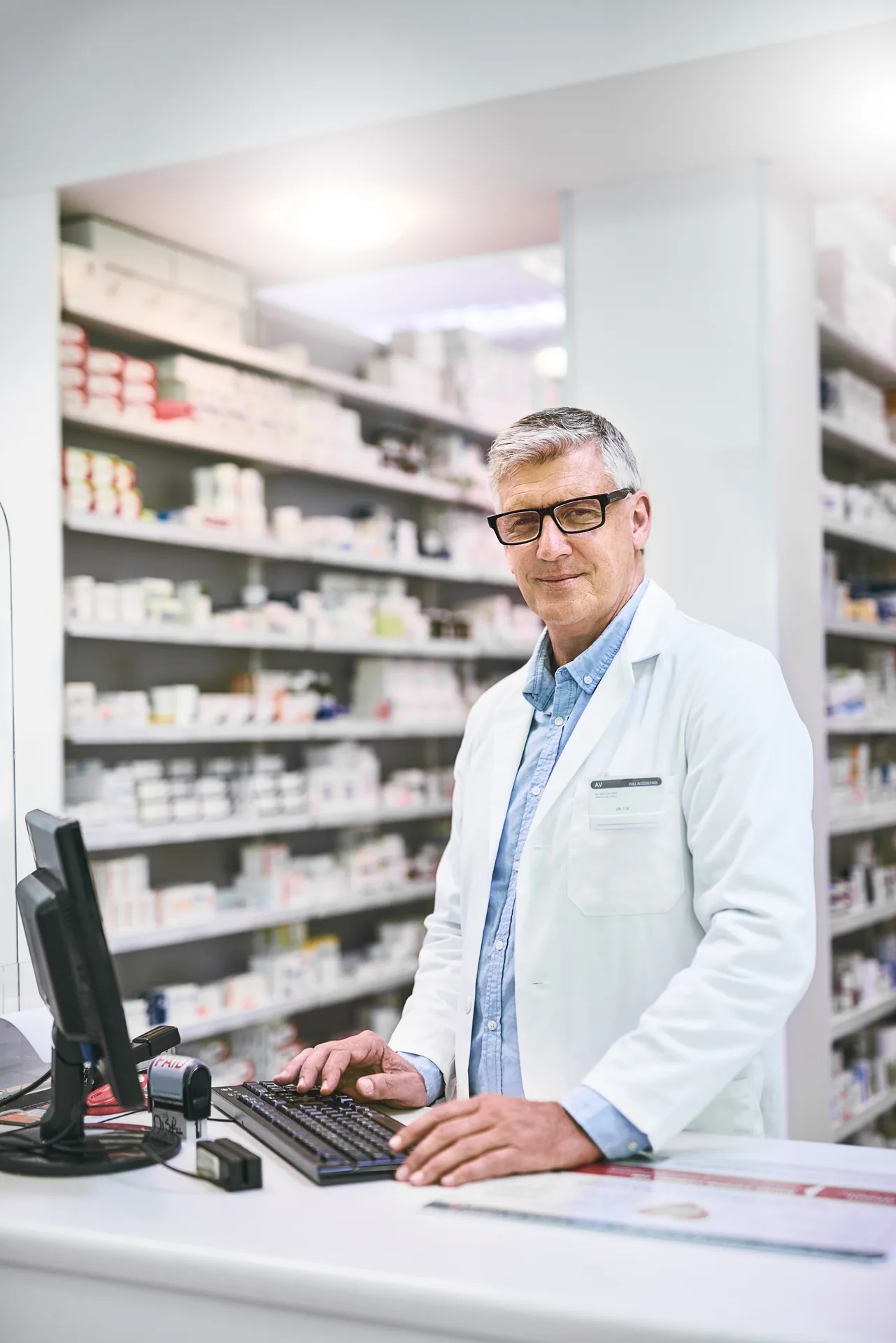Pharmacien à son ordinateur dans son officine – assurance de prêt pour pharmaciens