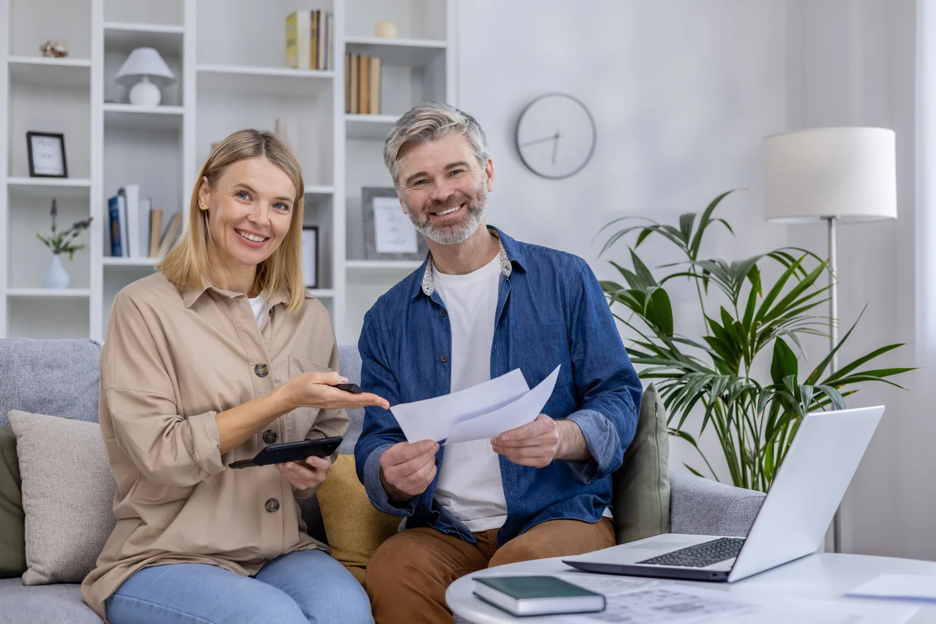 Un couple senior souriant examine ses documents d’épargne et de retraite